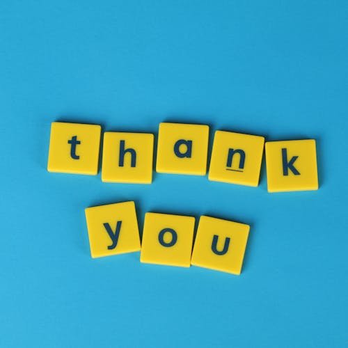 Bright yellow letter tiles spelling 'thank you' on a blue background, perfect for gratitude notes.